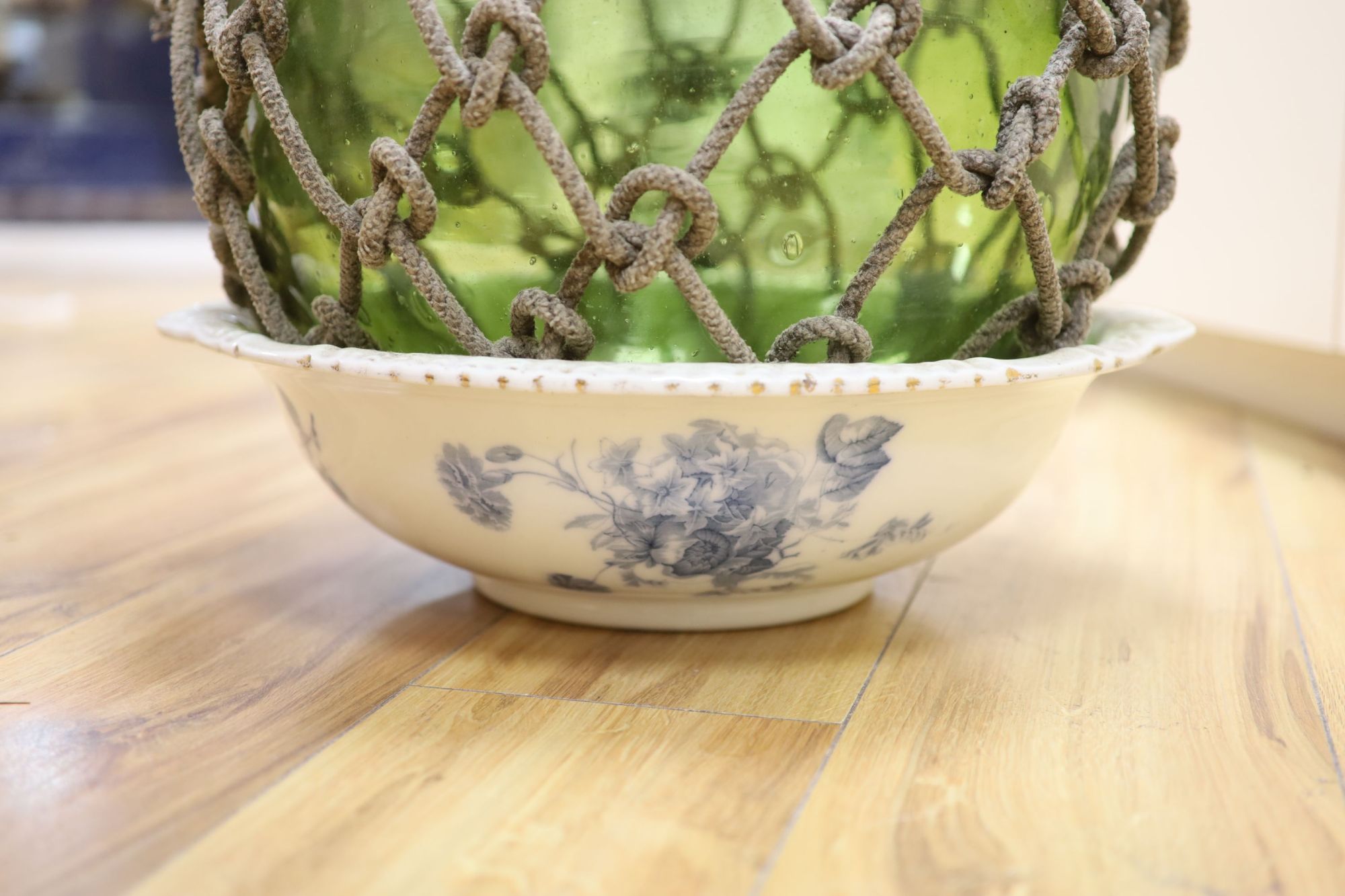 A large glass buoy with netting and a Staffordshire pottery basin